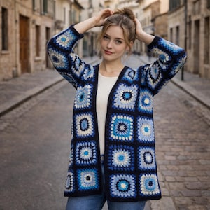 May include: A blue, white, and cream crochet cardigan with a square pattern. The open-front sweater is knee-length and has a classic granny square design. The cardigan is worn over a white top.