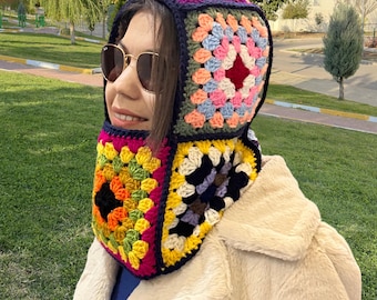 May include: A colourful crocheted hooded scarf with a granny square pattern in shades of pink, blue, green, yellow, orange, and black.