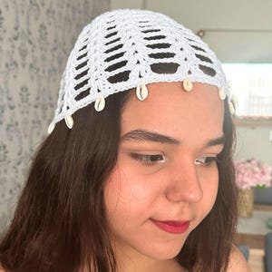 May include: White crochet hat with a shell trim. The hat is made of a delicate, open-weave fabric and has a simple, elegant design.