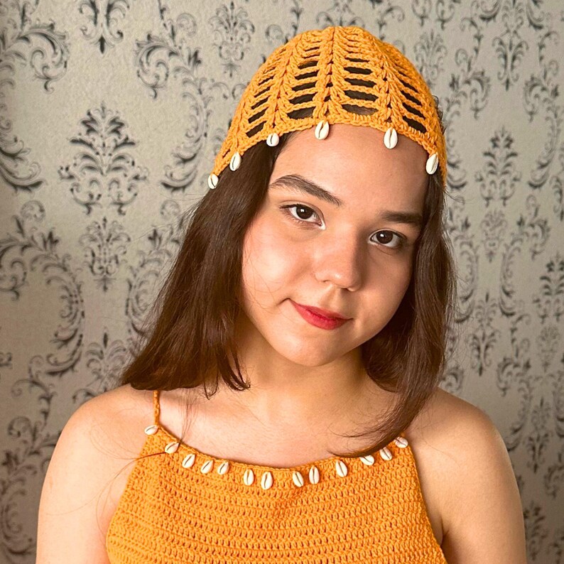 May include: A crocheted hat in a bright yellow color with white shell accents. The hat has a wide brim and a loose fit.