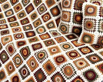 May include: A crocheted throw blanket and two matching pillow covers in a variety of autumnal colors, including brown, orange, green, and cream.