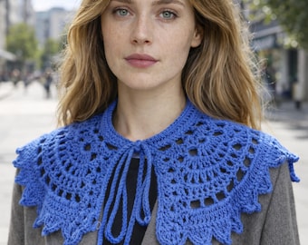 May include: A vibrant blue crochet collar with a scalloped edge and tie closure. The collar is worn over a gray coat, showcasing the intricate openwork design. This handmade accessory adds a touch of bohemian flair to any outfit.