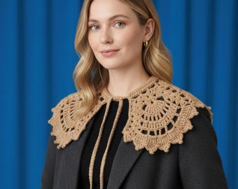 May include: A tan crochet collar with a scalloped edge and a tie closure. The collar is worn over a black top and a gray blazer. The background is a solid blue.