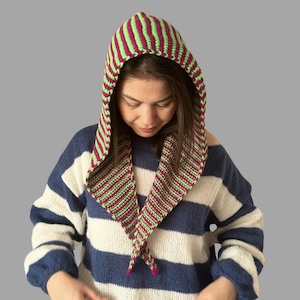 May include: A knitted hood in green and burgundy stripes. The hood is worn over the head and drapes down the front. The person in the image is wearing a blue and white striped sweater.