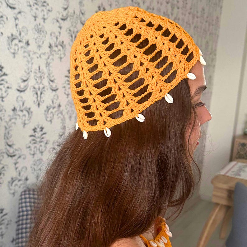 May include: A crocheted hat in a bright orange color with a white shell trim. The hat is made with a delicate open stitch pattern.