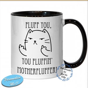 May include: White ceramic mug with a black handle and rim. The mug features a black and white illustration of a cat with an angry expression and the text "FLUFF YOU, YOU FLUFFIN' MOTHERFLUFFER!".