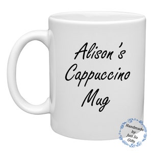 Peut inclure: Une tasse en c&eacute;ramique blanche avec une anse incurv&eacute;e. La tasse porte l'inscription "Alison's Cappuccino Mug" en &eacute;criture noire. Un petit motif circulaire avec du texte se trouve en bas &agrave; droite. La tasse est con&ccedil;ue pour les boissons.