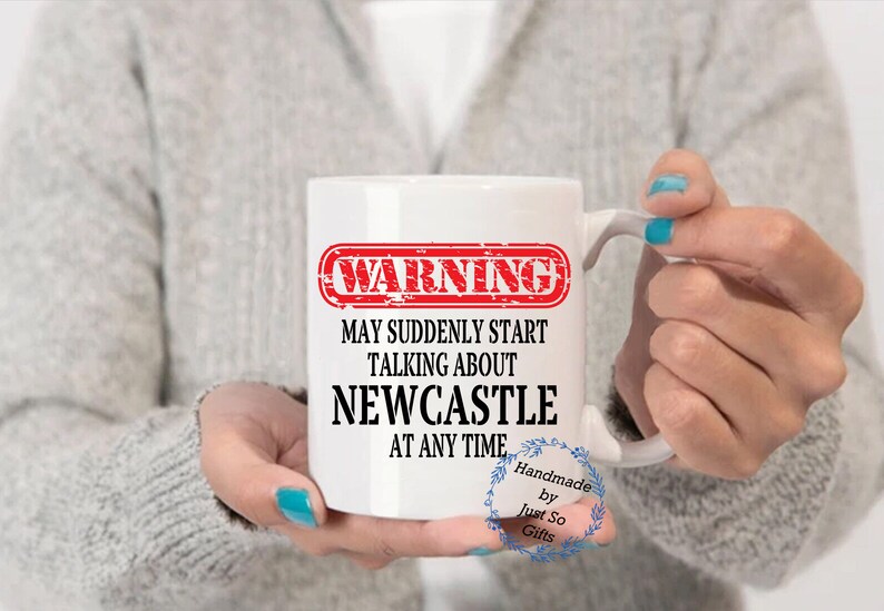 Peut inclure: Mug en c&eacute;ramique blanche avec le texte "WARNING MAY SUDDENLY START TALKING ABOUT NEWCASTLE AT ANY TIME" en noir et rouge. La tasse a une anse et est tenue par une personne. La tasse est faite &agrave; la main.