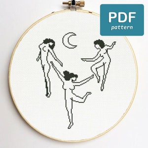 Può includere: Schema di punto croce con tre figure che danzano intorno a una luna crescente. Le figure sono delineate in nero e stilizzate con linee semplici.