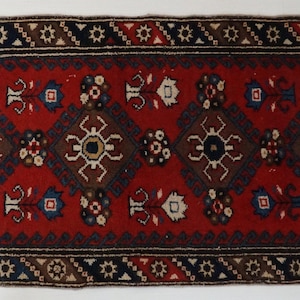 Può includere: Un tappeto runner rosso, blu e marrone con un design geometrico. Il tappeto ha frange su entrambi i lati.