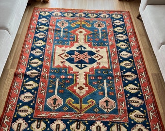 May include: A traditional Turkish rug with a blue, red, and cream color scheme. The rug features a geometric pattern with intricate details.