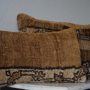 May include: Two brown and beige patterned throw pillows with fringe details. The pillows are made of a soft, woven fabric and have a rustic, bohemian style.