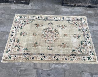 May include: A cream-colored rug with a floral pattern and a central medallion. The rug has a dark blue, green, and pink border.