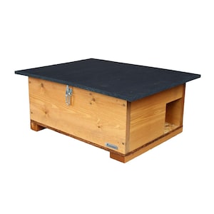 Puede incluir: Una casa de madera para erizos con un techo de asfalto negro y un pestillo de metal. La casa tiene un pequeño agujero de entrada y está diseñada para proporcionar refugio a los erizos.
