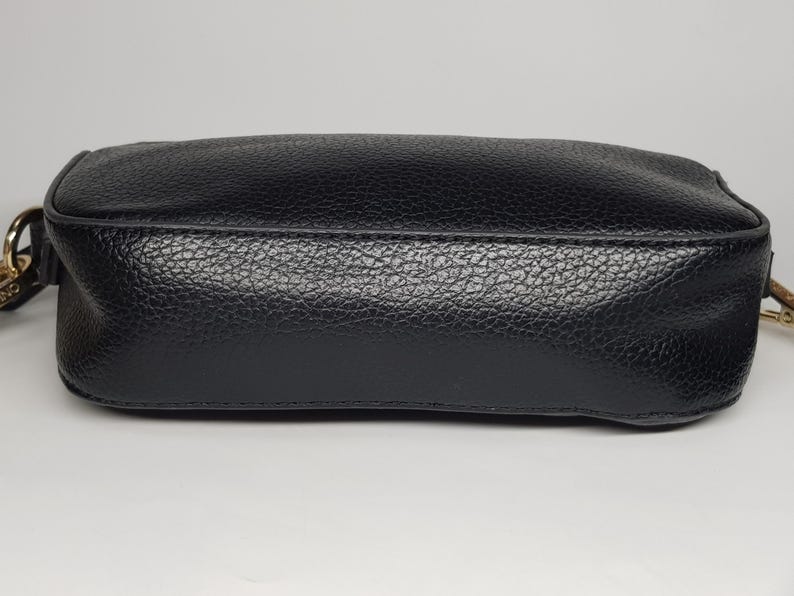 Pu&ograve; includere: Una borsa a tracolla in pelle nera con superficie strutturata. La borsa ha una forma rettangolare con bordi arrotondati e una tracolla a catena color oro. La borsa &egrave; mostrata su sfondo bianco.