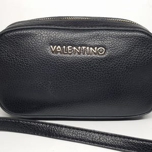 Pu&ograve; includere: Borsa a tracolla nera con finitura strutturata. La borsa presenta una cerniera e hardware dorati e il nome del marchio "VALENTINO" &egrave; visualizzato in lettere argentate sul davanti. Include una tracolla staccabile.
