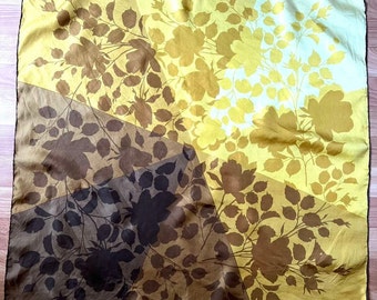 Peut inclure: Un foulard en soie jaune avec un motif géométrique de silhouettes florales brunes. Le foulard a une bordure brune et le texte "Hersey Paris" est imprimé dans le coin inférieur droit.