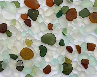 May include: A collection of sea glass in various colors, including white, green, brown, and blue. The sea glass is smooth and polished, with a variety of shapes and sizes.