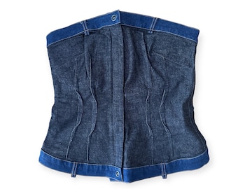 May include: A denim corset top with a blue trim and a button closure in the front.