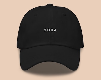 May include: A black baseball cap with the word "SOBA" embroidered in white on the front.