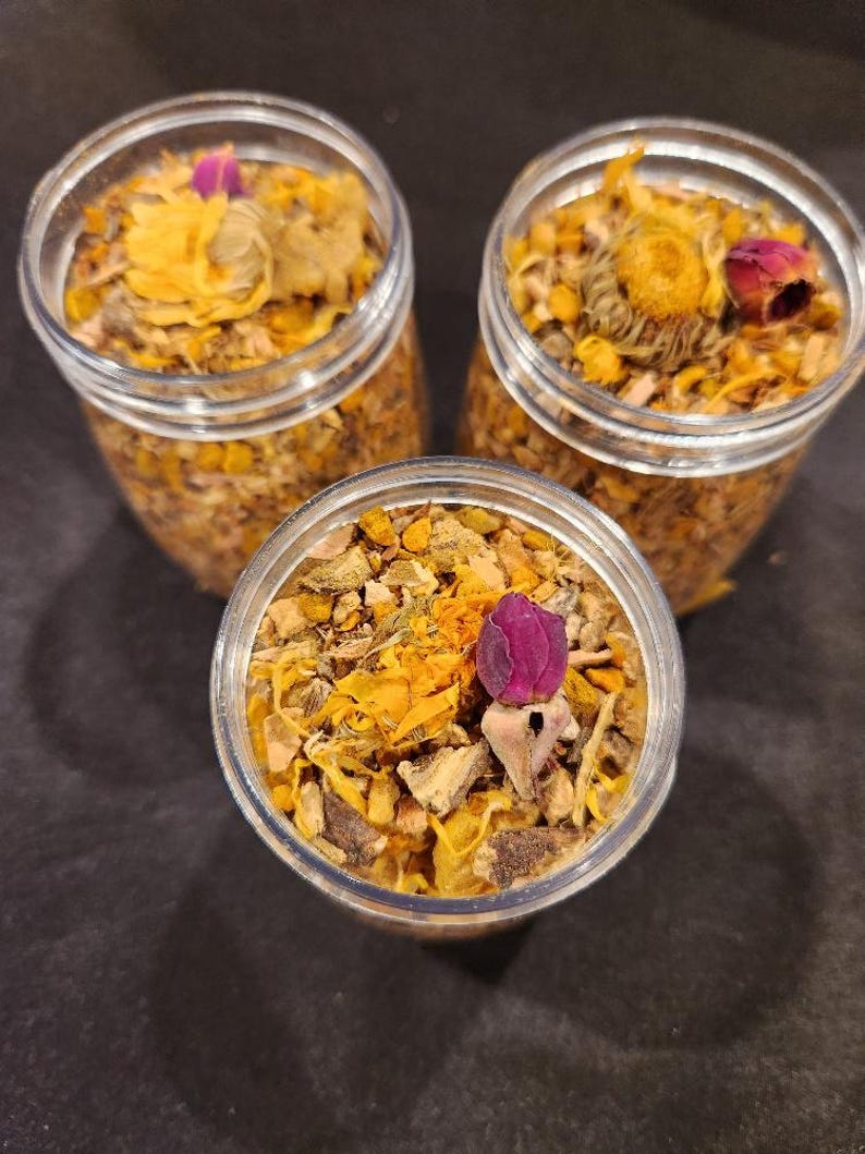 Puede incluir: Tres frascos de vidrio llenos de una mezcla de hierbas, flores y especias secas. Los frascos est&aacute;n llenos de una mezcla de ingredientes secos amarillos, naranjas y morados.