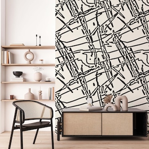 Puede incluir: Un papel tapiz de patrón abstracto en blanco y negro con una silla negra y un gabinete negro con una tapa de madera. El gabinete tiene dos puertas y está decorado con un patrón tejido.