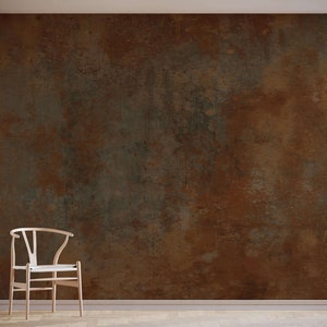 May include: A light wood chair with a white cushion sits in front of a wall with a rusty brown and green textured surface.