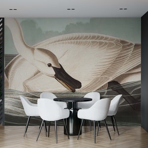 May include: A dining room with a black and white patterned wallpaper featuring a large white swan. The room has a round black table with four white chairs.