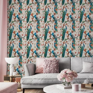 May include: A living room interior with a gray sofa, a coffee table, and a pink ottoman. The wall is covered in wallpaper featuring a repeating pattern of peacocks with blue and green feathers, perched on branches with orange flowers.