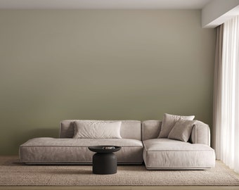 Può includere: Un divano angolare beige chiaro con due cuscini è posizionato su un tappeto marrone chiaro di fronte a una parete verde salvia. Un tavolino rotondo nero si trova di fronte al divano.