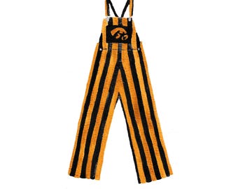 May include: Illustration of orange and black striped overalls with a black square patch on the bib. The patch features a logo. The overalls have adjustable straps and a classic overall design.