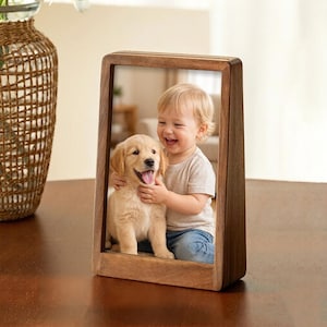 May include: A wooden picture frame with a photo of a smiling child hugging a golden retriever puppy. The frame is rectangular with a dark brown finish, and the photo is centered within the frame.