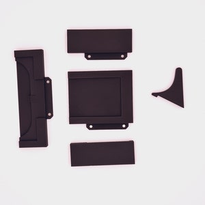 May include: A set of five black plastic pieces for a picture frame. The pieces include a top, bottom, two sides, and a back.