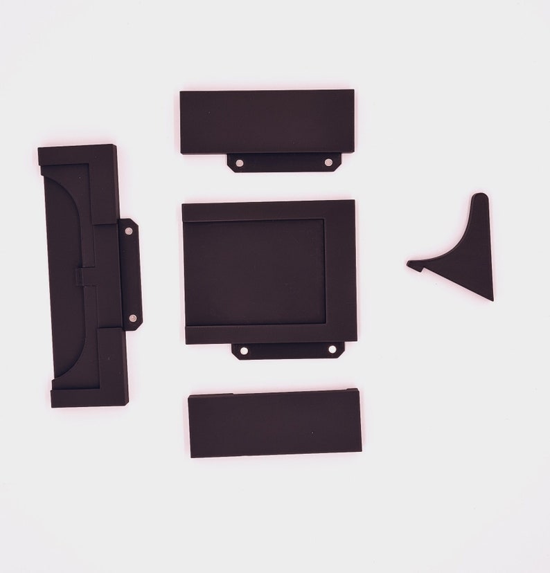 May include: A set of five black plastic pieces for a picture frame. The pieces include a top, bottom, two sides, and a back.