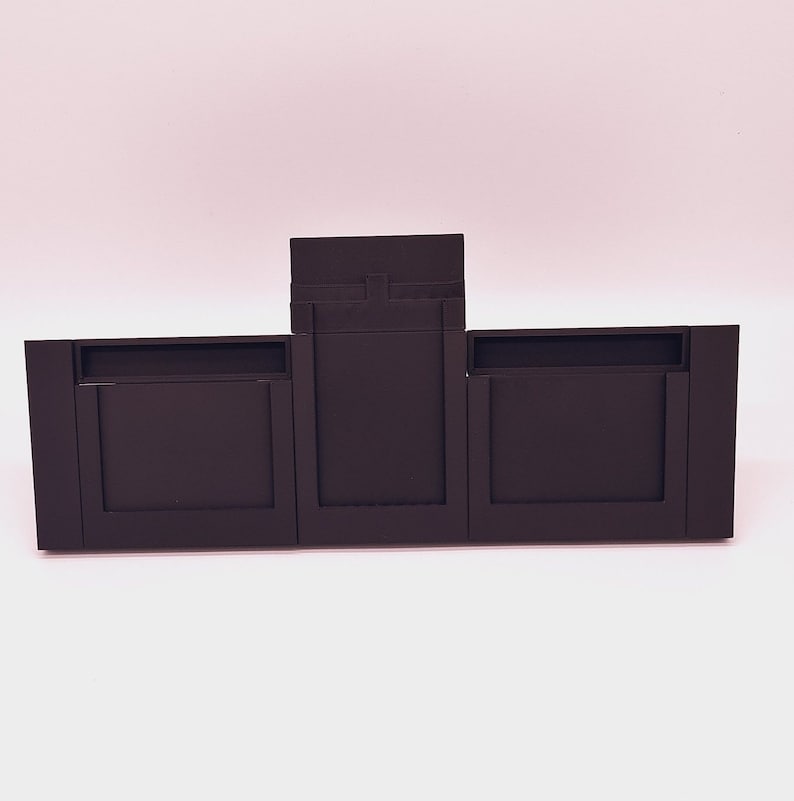 May include: Three black rectangular frames with a smaller black frame on top. The frames are made of a smooth, matte material.