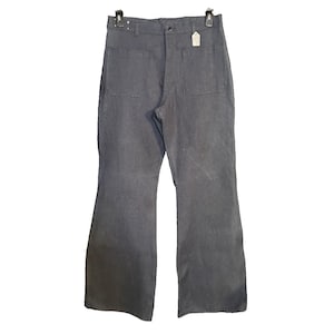 May include: Gray denim pants with a flared leg design. The pants have two back pockets and a button closure. A small tag is attached to the back. The pants are hanging from a black hanger.