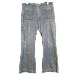 May include: Light blue denim jeans featuring a high-waisted design with a button and zipper fly closure. These pants include two large, square-shaped patch pockets on the front and a wide-leg silhouette that flares slightly toward the bottom hem.