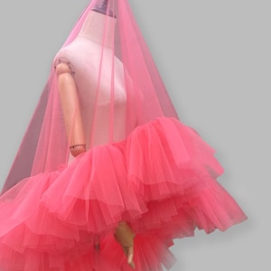 Op de afbeelding: Een roze tule rok met meerdere lagen wordt op een mannequin getoond. Een doorschijnende roze stof bedekt de mannequin en de tekst "OH! GIRL GANG" is linksboven zichtbaar.