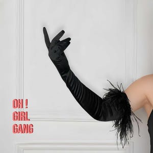 May include: Black satin opera gloves with a feather trim. The gloves extend to the elbow. The text "OH! GIRL GANG" is visible in the background.