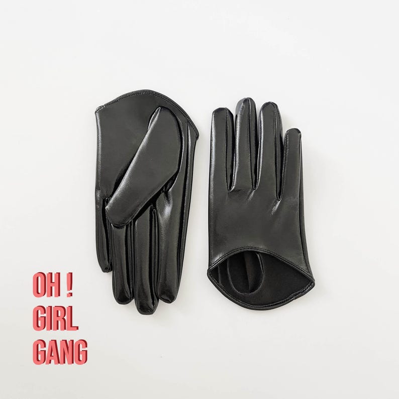 Puede incluir: Un par de guantes de piel sint&eacute;tica negra con un acabado liso y brillante. Un guante est&aacute; doblado, mientras que el otro muestra un detalle recortado en la mu&ntilde;eca. El texto OH ! GIRL GANG est&aacute; impreso en letras rojas a la izquierda.
