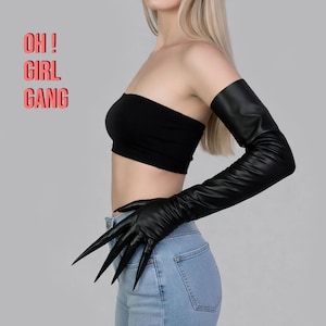 May include: Black faux leather gloves with long, sharp claws. The gloves extend up the arm. The image also includes a black tube top and the text "OH! GIRL GANG" in a pink box.