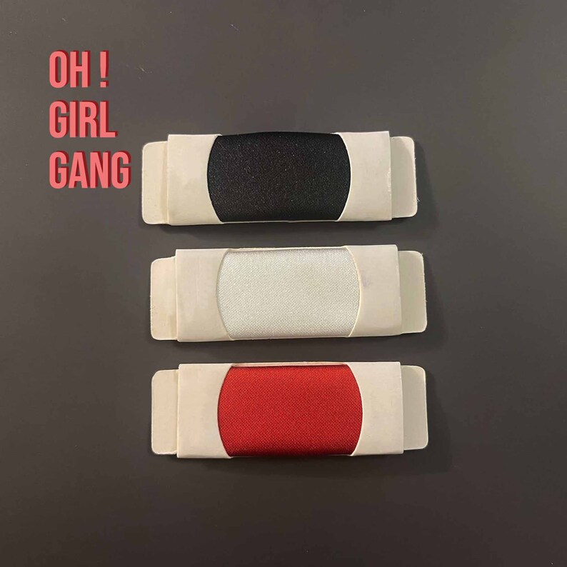 May include: Three fabric swatches in white, black, and red, each displayed in a white cardboard frame. The text "OH! GIRL GANG" is written in red above the swatches.
