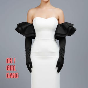 Op de afbeelding: Een strapless witte jurk met zwarte geplooide mouwen en lange zwarte handschoenen. De tekst "OH! GIRL GANG" is roze gedrukt. De jurk heeft een elegante, nauwsluitende pasvorm.