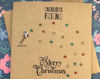 May include: A kraft paper Christmas card with the words "Fabulous Friend" and "Merry Christmas" in black script. The card features a star-shaped design with colorful star embellishments and a silver star charm that reads "a special wish."