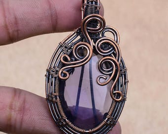 May include: A handcrafted pendant with a teardrop-shaped amethyst stone, intricately wrapped in copper and silver-colored wire. The pendant features decorative copper swirls and a bail for a necklace chain.