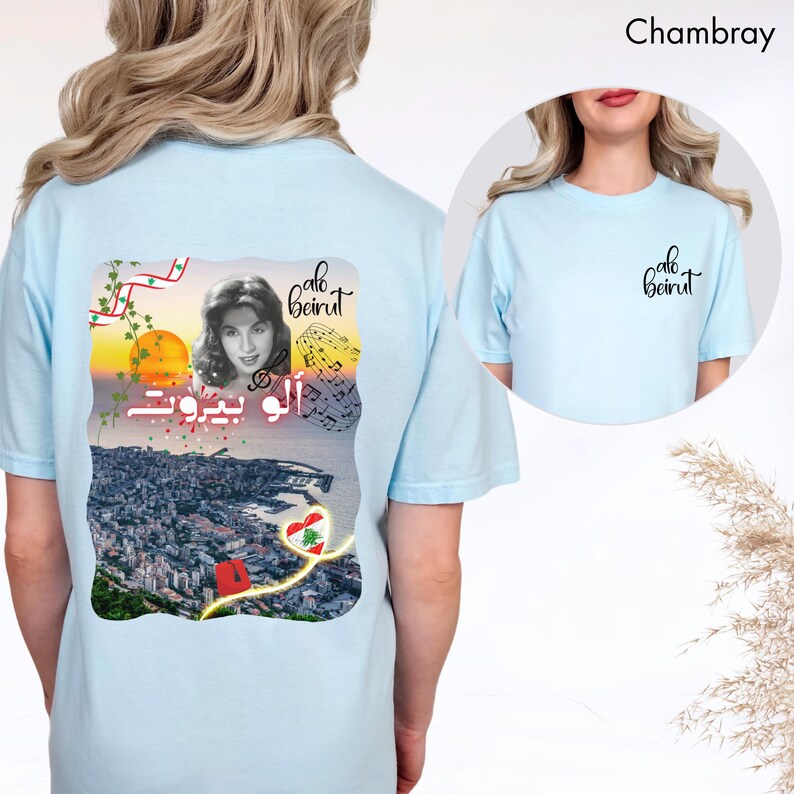 Puede incluir: Una camiseta azul claro con un gr&aacute;fico en la espalda que muestra un retrato en blanco y negro de una mujer, notas musicales, un atardecer sobre una ciudad, un fez rojo y un coraz&oacute;n con la bandera libanesa. El texto dice Alo Beirut.