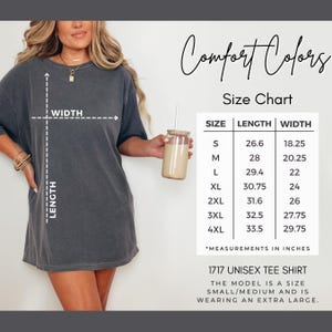 Puede incluir: Una camiseta gris carb&oacute;n de manga corta con una tabla de tallas Comfort Colors. La tabla enumera las tallas de la S a la 4XL con las medidas de largo y ancho en pulgadas. El texto 1717 UNISEX TEE SHIRT aparece en la parte inferior.