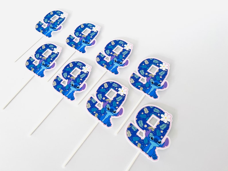 Puede incluir: Un conjunto de nueve adornos para tartas con el n&uacute;mero nueve y el personaje Stitch de Lilo & Stitch. Cada adorno tiene un n&uacute;mero nueve azul con una ilustraci&oacute;n de Stitch y un palito blanco. El fondo del n&uacute;mero nueve es un patr&oacute;n azul.