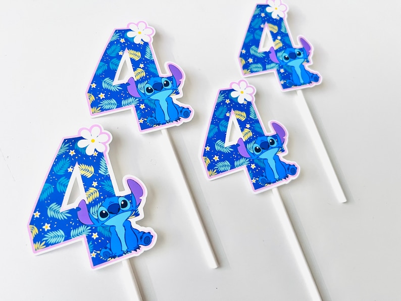 Puede incluir: Cuatro adornos para tartas con el personaje Stitch de Lilo & Stitch. Cada n&uacute;mero cuatro est&aacute; decorado con un patr&oacute;n de hojas tropicales azules y un personaje Stitch. Una flor blanca corona cada n&uacute;mero. Los adornos est&aacute;n sobre palitos blancos.