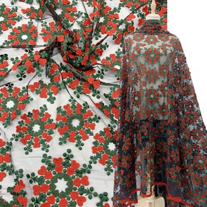 May include: Black mesh fabric with red and green embroidered hearts. The fabric is shown draped over a mannequin.